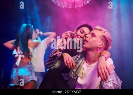 Guy taking drug pill. Young people is having fun in night club with colorful laser lights Stock Photo