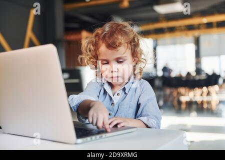 Smart child in casual clothes using laptop for education purposes or fun Stock Photo