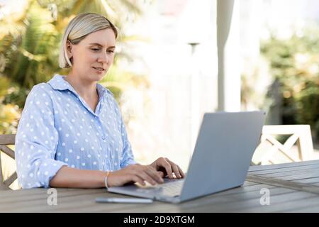 Young business woman working at the laptop outdoors. Happy smile. Stock Photo