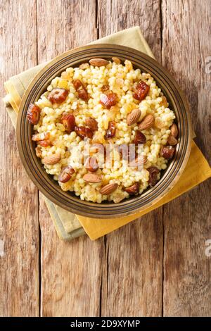 Sweet couscous with almonds, raisins and dates close-up in a plate on the table. Horizontal top view from above Stock Photo