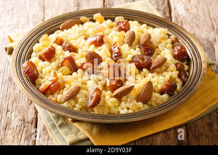 Mesfouf  super-soft steamed sweet buttery couscous with dried fruits and nuts close-up in a plate on the table. horizontal Stock Photo