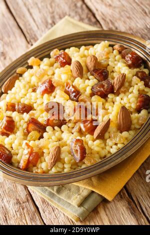 Mesfouf or masfouf is an Algerian, Moroccan and Tunisian dish which sweet couscous with dried fruits and nuts close-up in a plate on the table. vertic Stock Photo