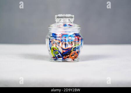 a wide view of a jar of multi colored can pull tabs Stock Photo