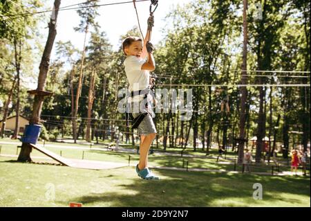 Little brave boy on zipline in rope park Stock Photo