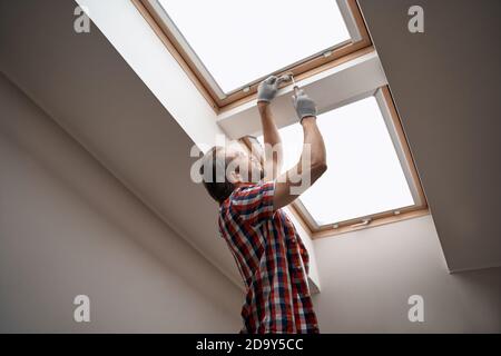 Young caucasian worker screwing skylight window handle Stock Photo