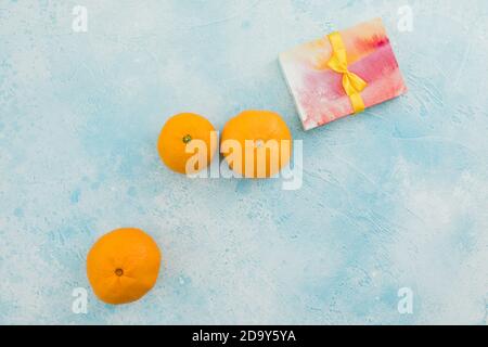 Mandarin fruits with gift box and blue background. Flat lay Stock Photo