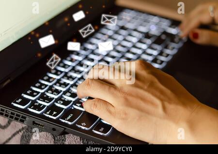 Closeup shot of female hands using keyboard computer laptop with flying e-mail icons. Business technology concept Stock Photo