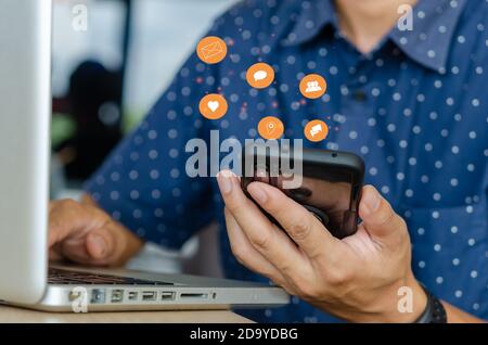 Closeup shot of male hands using smartphone with flying social media icons. Business technology concept Stock Photo