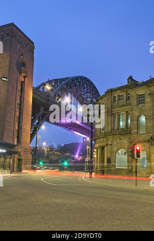 Light trails down on Newcastle's quayside looking towards the Tyne Bridge and Guildhall at dawn.