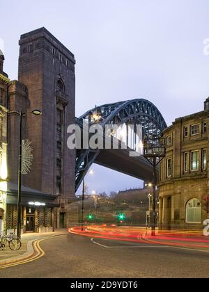 Light trails down on Newcastle's quayside looking towards the Tyne Bridge and Guildhall at dawn.