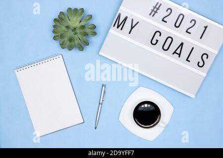Blank notebook, pen, coffee cup, lightbox with My Goals text on office desk. Plans for the coming year concept Stock Photo