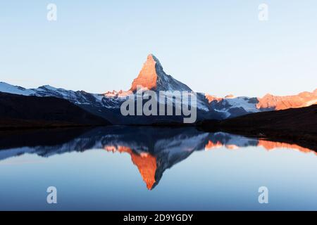 Picturesque landscape with colorful sunrise on Stellisee lake. Snowy Matterhorn Cervino peak with reflection in clear water. Zermatt, Swiss Alps Stock Photo