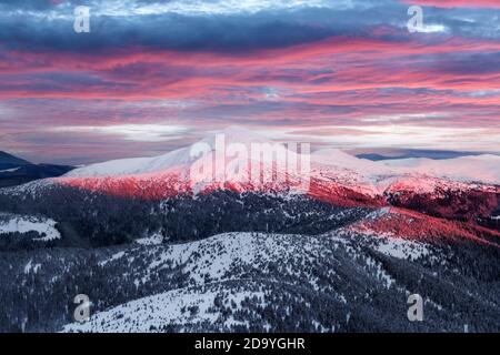 Fantastic orange winter landscape in snowy mountains glowing by sunlight. Dramatic wintry scene with snowy trees. Christmas holiday background