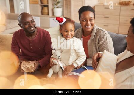 Magical portrait of happy African-American family exchanging Christmas gifts while enjoying holiday season at home Stock Photo
