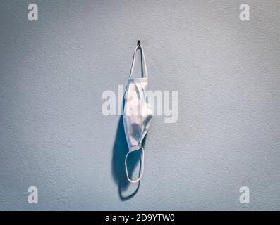 Still-life of a disposable protective mask hanging on a wall. Stock Photo