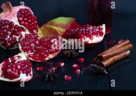 Large pomegranate, broken into pieces. On a dark background. Grains are scattered nearby. Autumn concept. Vitamins, healthy lifestyle. Copy space. Stock Photo