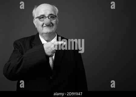 Overweight senior businessman wearing clown's nose against brown background Stock Photo