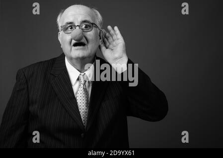 Overweight senior businessman wearing clown's nose against brown background Stock Photo