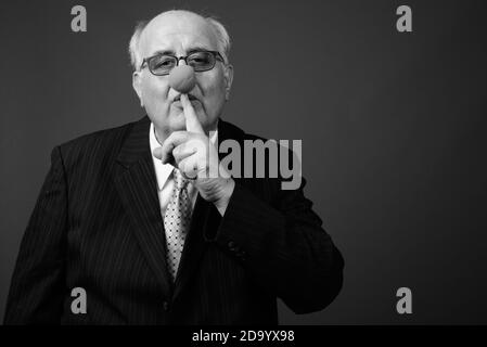 Overweight senior businessman wearing clown's nose against brown background Stock Photo