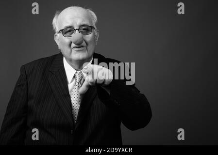 Overweight senior businessman wearing clown's nose against brown background Stock Photo