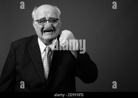 Overweight senior businessman wearing clown's nose against brown background Stock Photo