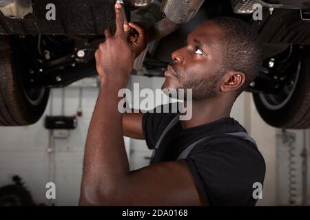 repairing in action. hardworking guy employee in uniform works in the automobile salon, confident auto mechanic is professional worker of service Stock Photo