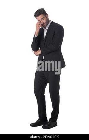 Full length portrait of young handsome business man in black suit feeling stress or depression studio isolated on white background Stock Photo