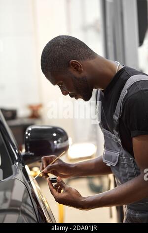 african man's hands use the detail brush to paint car or to clean and remove the dirt, car detailing and car wash painting concept Stock Photo