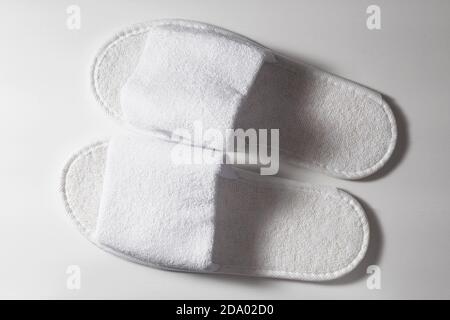 Top view of white slippers on a white wooden background Stock Photo