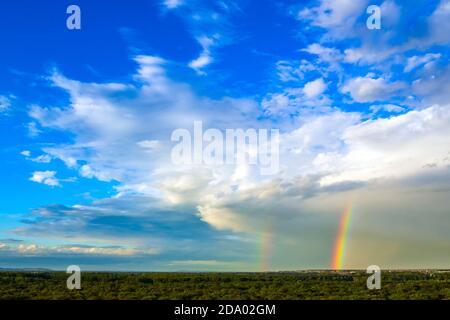 Landscape green forest, blue sky with white clouds and double rainbow Stock Photo