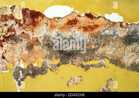 old yellow painted wall with cracks of cement background with red, white and gray stains Stock Photo
