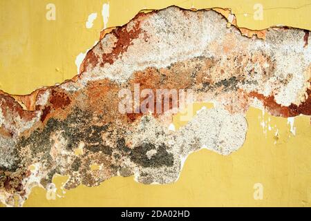 old yellow painted wall with cracks of cement background with red, gray and white stains Stock Photo
