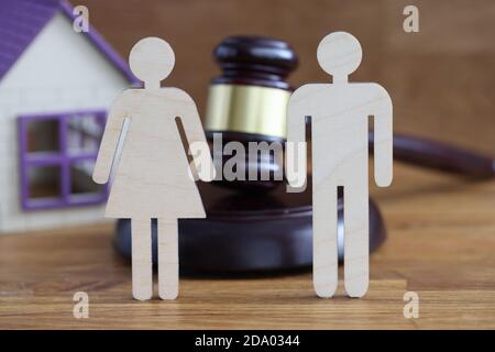 Wooden figures of man and woman standing on table near judges hammer and toy house closeup Stock Photo