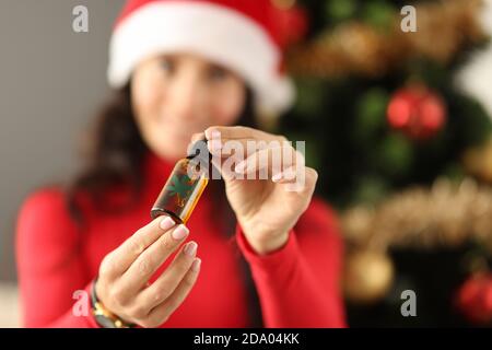 Young woman in santa claus hat holding a bottle with marijuana extract closeup Stock Photo
