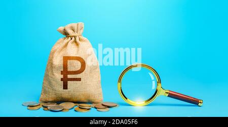 Russian ruble money bag and magnifying glass. Revising the budget to save money. Financial audit control. Most favorable conditions for deposits. Orig Stock Photo