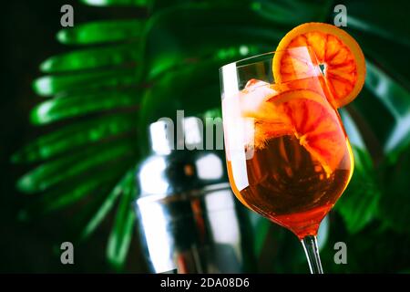 Aperol spritz cocktail in big wine glass with bloody oranges, summer Italian fresh alcohol cold drink. Wooden bar counter background with tools, summe Stock Photo