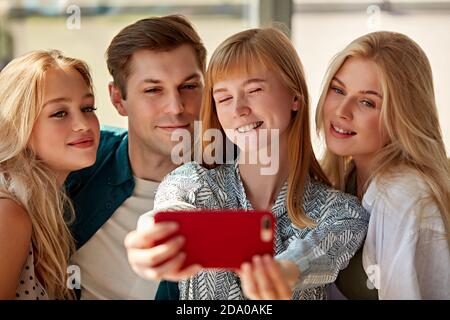 overjoyed caucasian people posing for photo in cafe together, take selfie on smartphone, posing for photo in cafe together, recording video for social network, having fun with friends Stock Photo