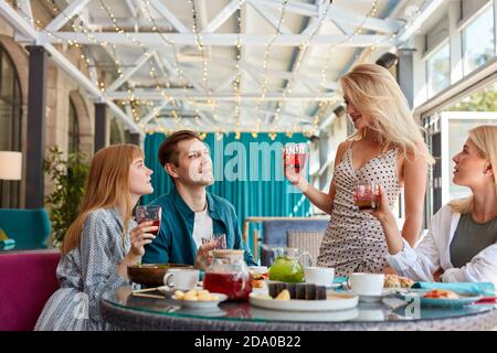 cheerful caucasian friends spending time together in bright cozy time cafe, they have fun, talk, chatting. lunch time or they celebrating something, entertaining Stock Photo