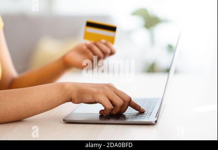Black woman using laptop and credit card at home Stock Photo