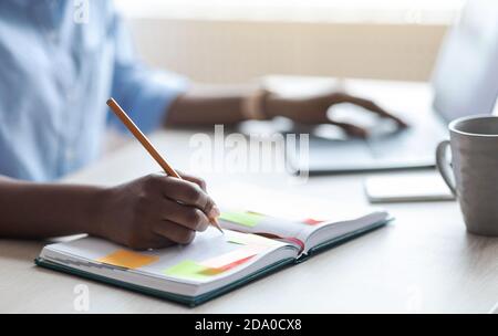 Busy Unrecognizable Woman Writing In Notepad, Taking Notes At Workplace In Office Stock Photo