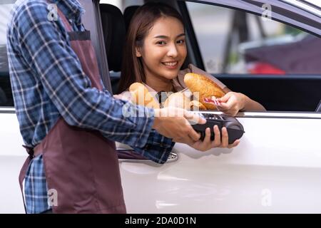 Portrait of asian woman make mobile payment contactless technology for online grocery ordering and drive thru service. Drive through and food online i Stock Photo