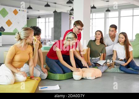 group of young diverse people practice first aid training by hand, first aid course in CPR dummy. concept of training skills to save lives, medicine Stock Photo