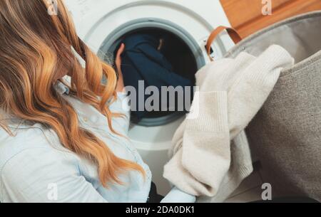 Woman loading clothes into washing machine. Stock Photo