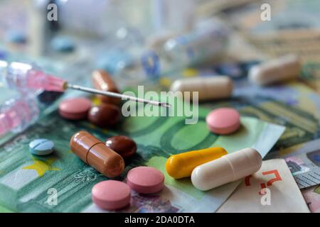 A lot of pills and capsules lie on the banknotes. Tax deduction for expenses for expensive treatment Stock Photo