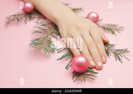 Close up womans hands holding a fir tree branch with pink balls and beads  Stock Photo