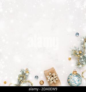Christmas snowy white background with gift, fir twigs, gold blue decorations. Copy space. Christmas frame. Stock Photo