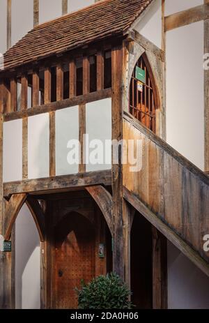 An historic half-timbered building. A door sits under a gallery and a stairway runs up the side to an iron gate. Stock Photo