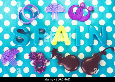 Top view shot of the word "Spain" made of plastic letters and castanets on blue dotted background Stock Photo