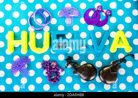 Top view shot of the word "Huelva" made of plastic letters and castanets on blue dotted background Stock Photo