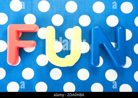 Top view shot of the word "Fun" made of plastic letters on blue dotted background Stock Photo